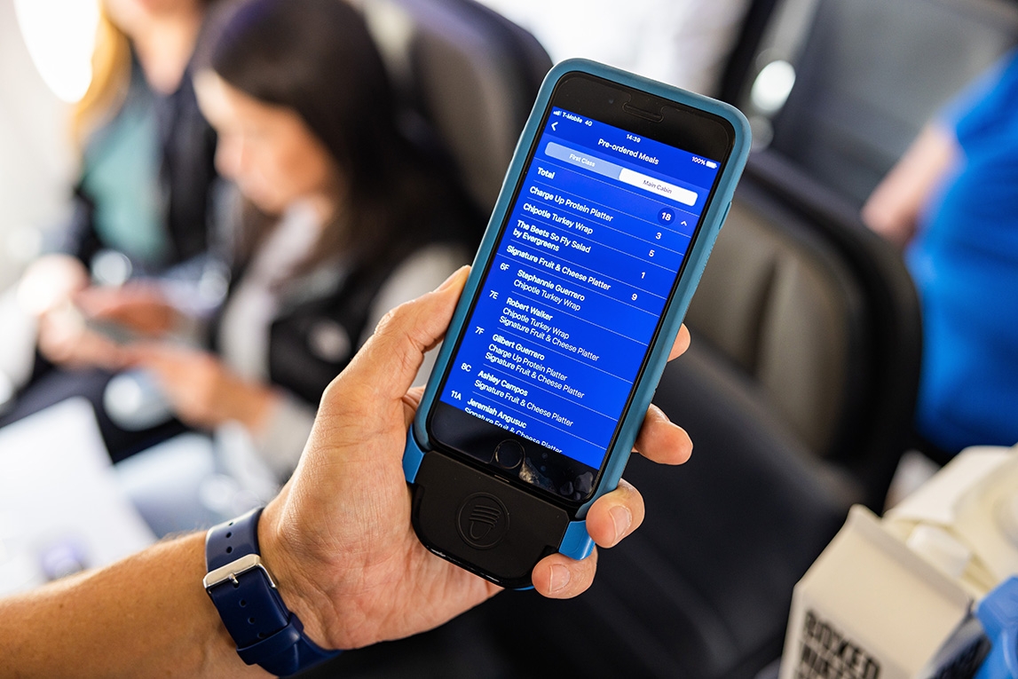 Alaska Airlies Flight attendant holding new crew app with Ditto's technology built in